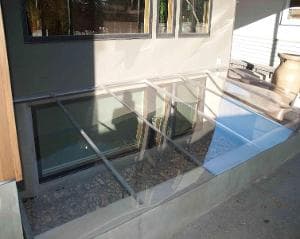 Modern glass skylight over a basement window, enhancing natural light for outdoor spaces.